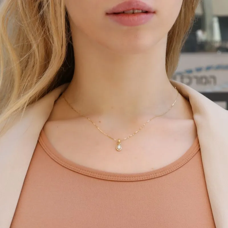 A drop-shaped halo pendant with a white opal stone on a 14K gold chain.